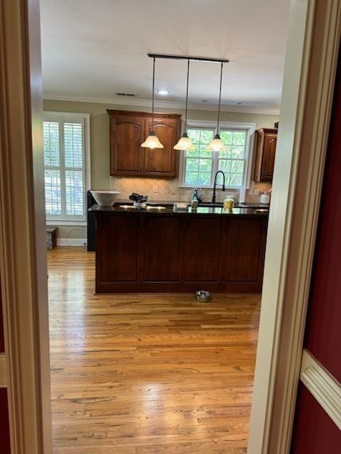 kitchen with track lighting, sink, light hardwood / wood-style flooring, ornamental molding, and decorative light fixtures