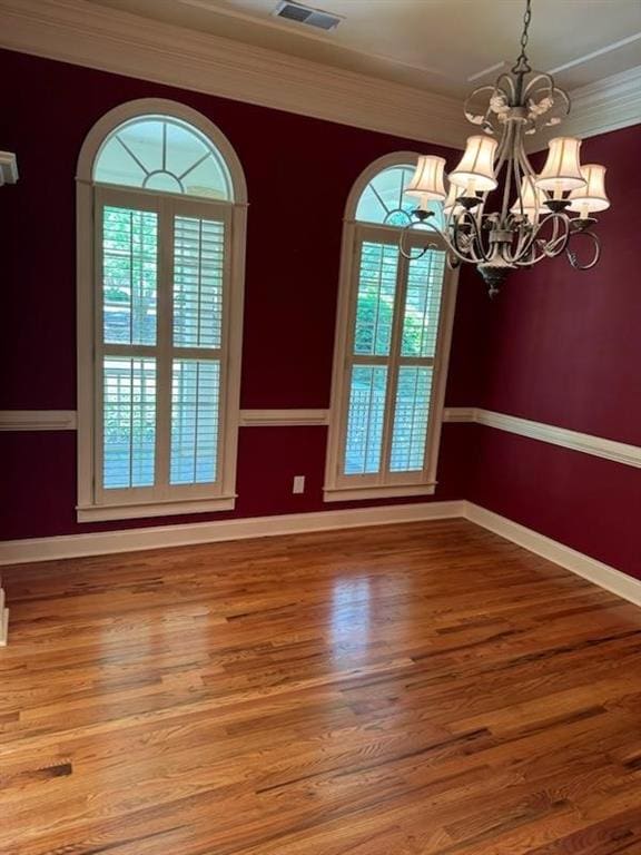 unfurnished dining area featuring a healthy amount of sunlight, crown molding, and a chandelier