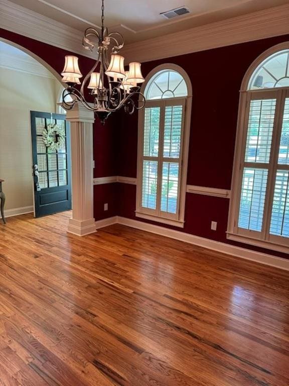 unfurnished dining area with a healthy amount of sunlight, decorative columns, ornamental molding, and a notable chandelier