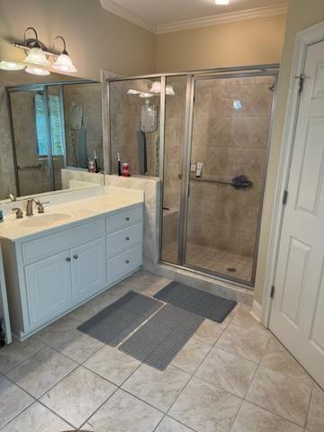 bathroom featuring tile patterned flooring, ornamental molding, vanity, and a shower with shower door