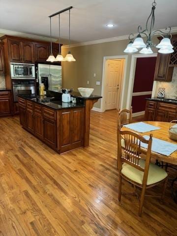 kitchen featuring a center island, backsplash, decorative light fixtures, appliances with stainless steel finishes, and a notable chandelier