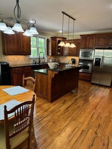 kitchen with backsplash, hanging light fixtures, and appliances with stainless steel finishes