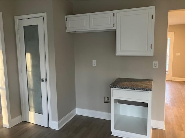 kitchen with dark wood-type flooring, white cabinets, and baseboards