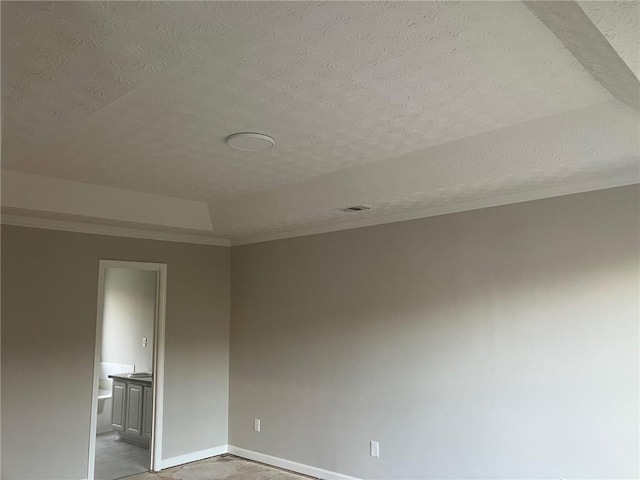 spare room with a textured ceiling, crown molding, and baseboards