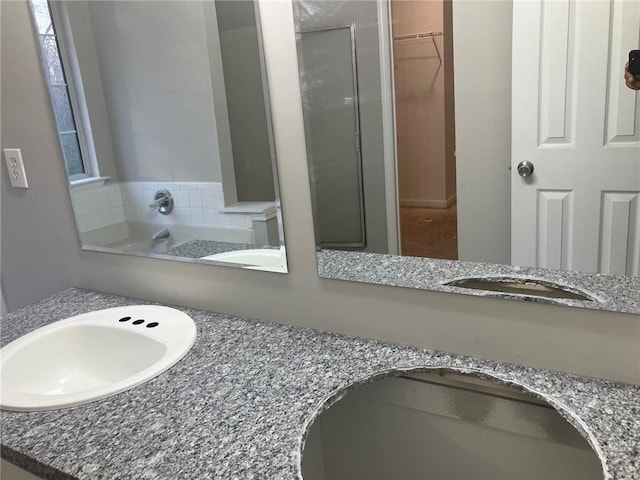 full bathroom with double vanity, a spacious closet, a bath, and a sink