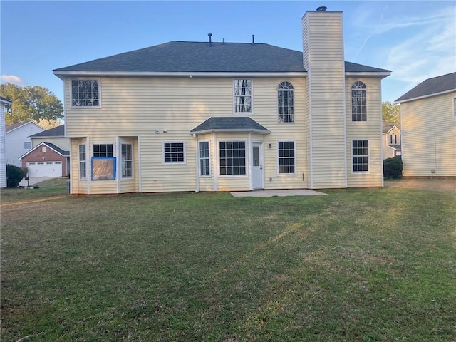 back of house featuring a patio area, a chimney, a yard, and roof with shingles