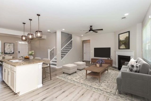 living room featuring ceiling fan, light hardwood / wood-style flooring, and sink