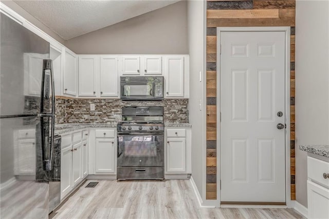 459 Bakers Bridge Cir, Douglasville, GA 30134 - kitchen featuring black appliances, backsplash, light wood-style flooring, white cabinets, and lofted ceiling