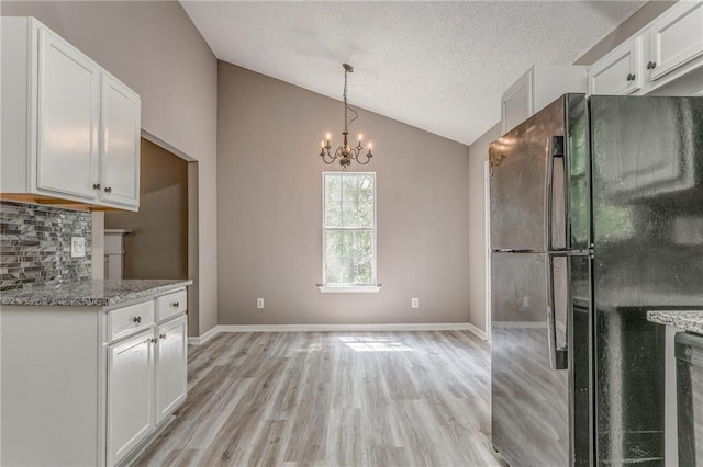 459 Bakers Bridge Cir, Douglasville, GA 30134 - kitchen featuring freestanding refrigerator, lofted ceiling, a chandelier, white cabinets, and tasteful backsplash