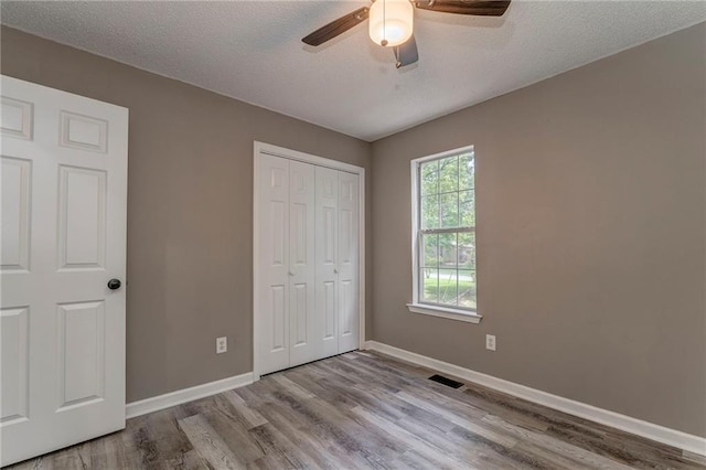 459 Bakers Bridge Cir, Douglasville, GA 30134 - unfurnished bedroom featuring wood finished floors, baseboards, a closet, a textured ceiling, and a ceiling fan