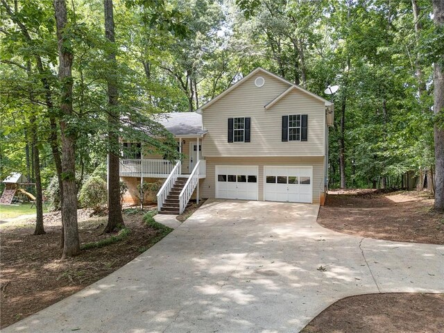 459 Bakers Bridge Cir, Douglasville, GA 30134 - tri-level home with an attached garage, concrete driveway, stairs, and view of scattered trees