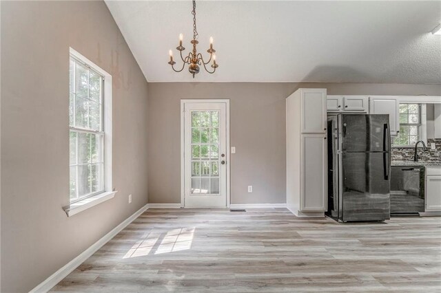 459 Bakers Bridge Cir, Douglasville, GA 30134 - unfurnished dining area featuring a chandelier, light wood-style floors, a sink, lofted ceiling, and baseboards