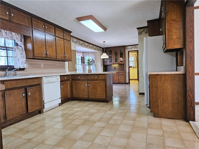 kitchen with hanging light fixtures, sink, a wealth of natural light, and white appliances