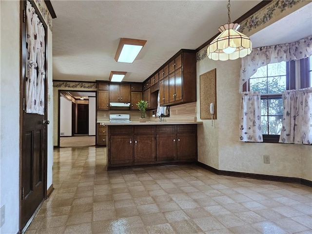 kitchen featuring pendant lighting, sink, dark brown cabinetry, and stove