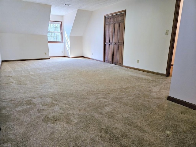 additional living space with light colored carpet and a textured ceiling