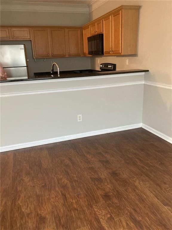 kitchen featuring dark hardwood / wood-style flooring, stainless steel refrigerator, ornamental molding, and sink