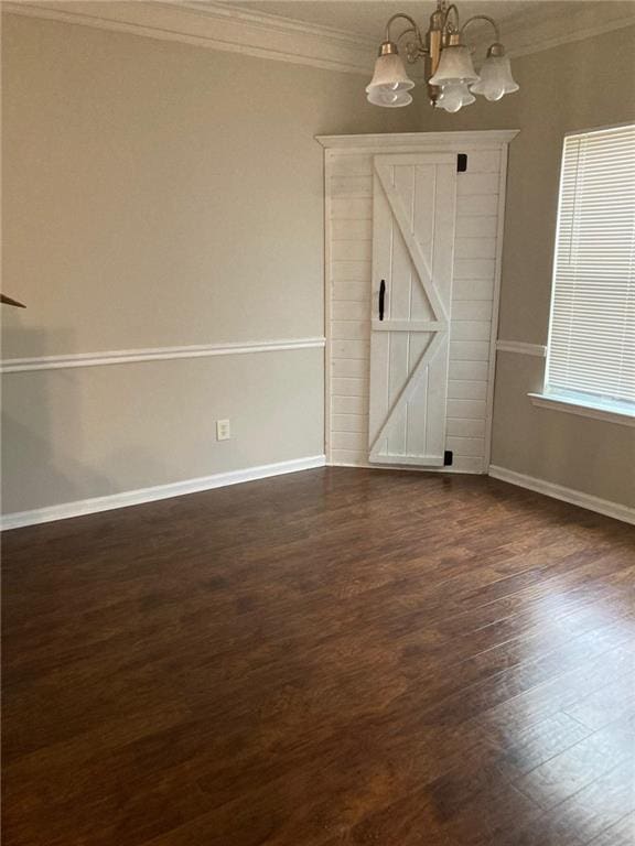 spare room featuring dark wood-type flooring, ornamental molding, and a notable chandelier