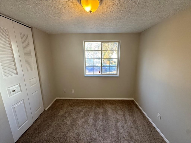 unfurnished bedroom with dark colored carpet, a textured ceiling, and a closet