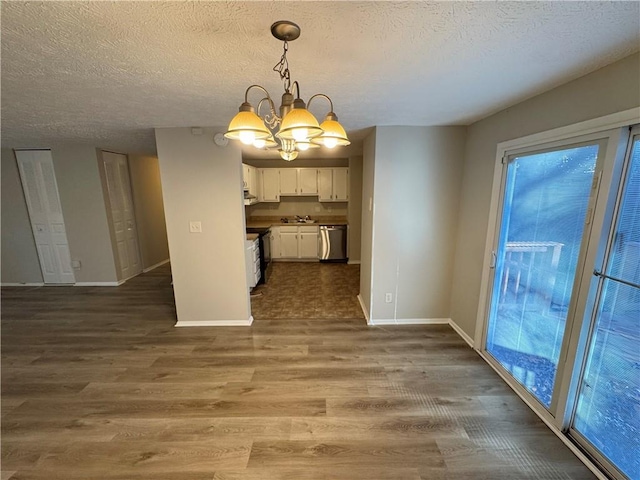 unfurnished dining area featuring a chandelier, a textured ceiling, and dark hardwood / wood-style flooring