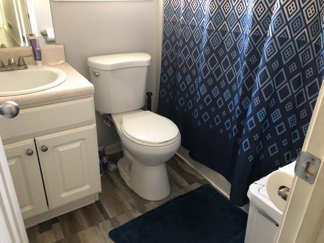 bathroom featuring curtained shower, hardwood / wood-style floors, vanity, and toilet