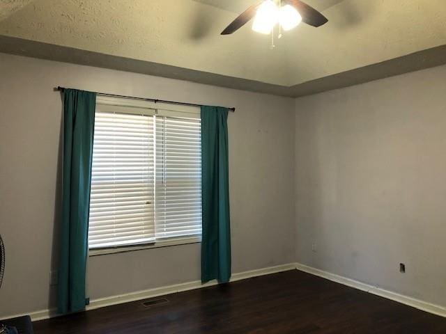 empty room featuring lofted ceiling, ceiling fan, and dark hardwood / wood-style floors