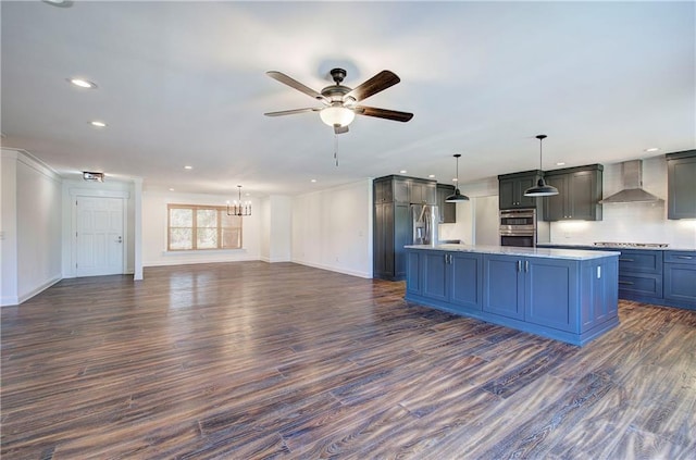 kitchen featuring ceiling fan with notable chandelier, dark hardwood / wood-style flooring, decorative light fixtures, and wall chimney exhaust hood