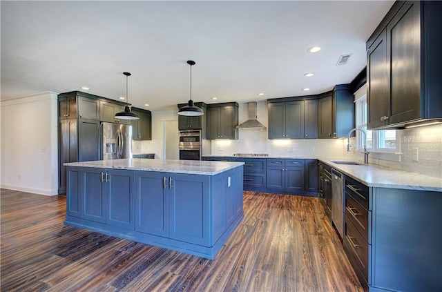 kitchen with a center island, sink, stainless steel appliances, wall chimney range hood, and decorative light fixtures