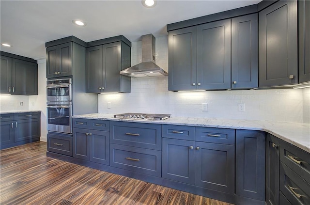 kitchen featuring dark hardwood / wood-style floors, wall chimney range hood, backsplash, and appliances with stainless steel finishes