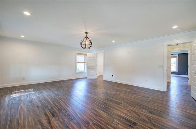 unfurnished room with a notable chandelier, dark hardwood / wood-style flooring, and ornamental molding