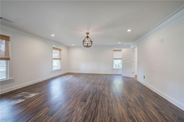 empty room with dark hardwood / wood-style floors, crown molding, and an inviting chandelier