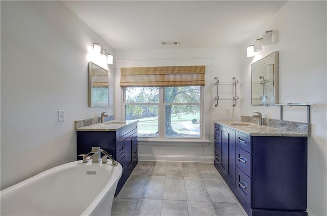 bathroom featuring tile patterned flooring, vanity, and a tub to relax in