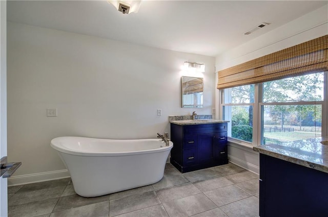 bathroom with a washtub, vanity, and tile patterned floors