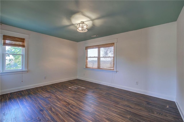 spare room with plenty of natural light and dark hardwood / wood-style flooring