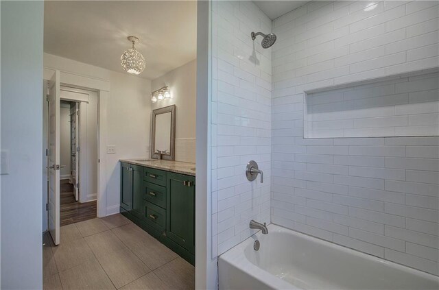 bathroom with vanity, tiled shower / bath combo, and a notable chandelier