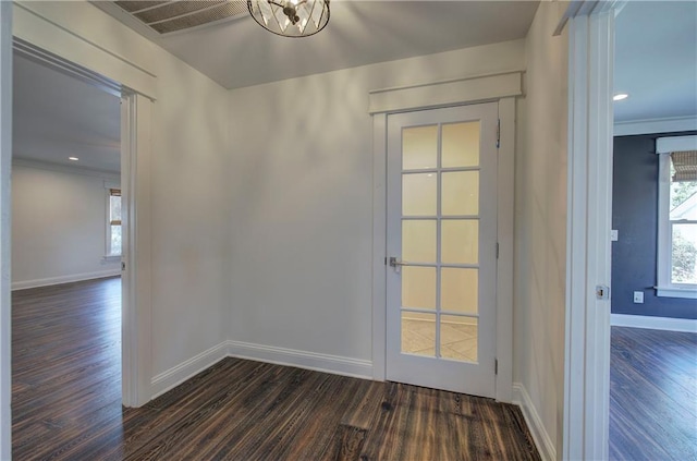 doorway to outside featuring a notable chandelier, dark hardwood / wood-style flooring, and ornamental molding