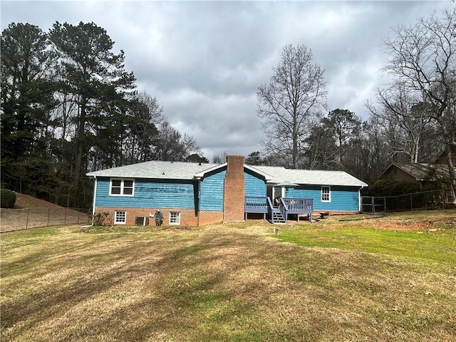 back of property featuring a deck and a lawn