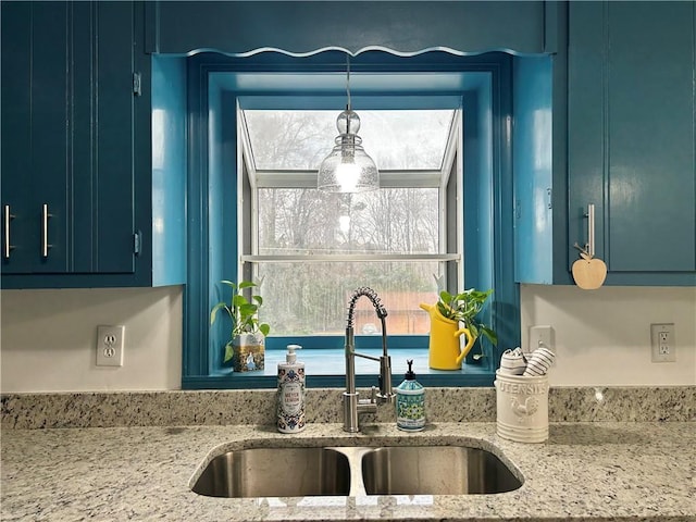 kitchen with plenty of natural light, light stone countertops, sink, and hanging light fixtures