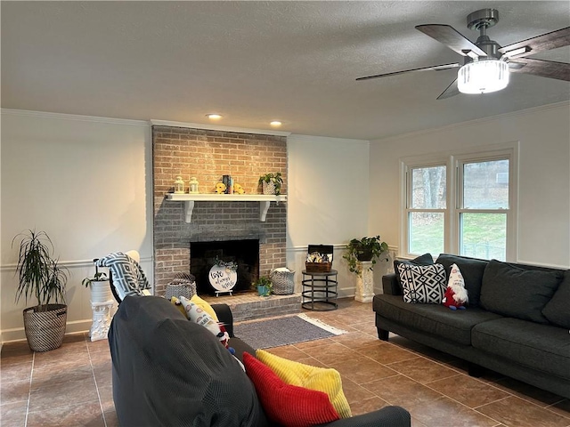 living room with a textured ceiling, ornamental molding, dark tile patterned floors, ceiling fan, and a fireplace