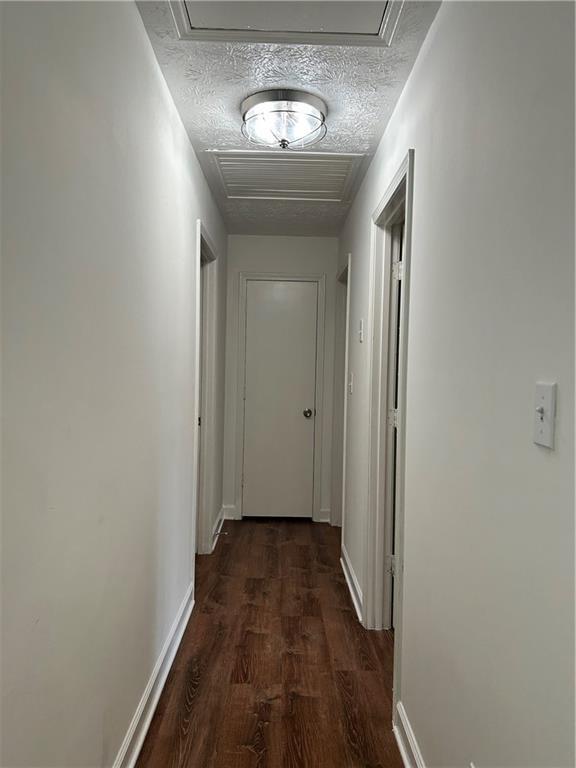 hall with dark hardwood / wood-style floors and a textured ceiling