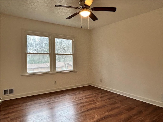 empty room with ceiling fan, dark hardwood / wood-style floors, and a textured ceiling