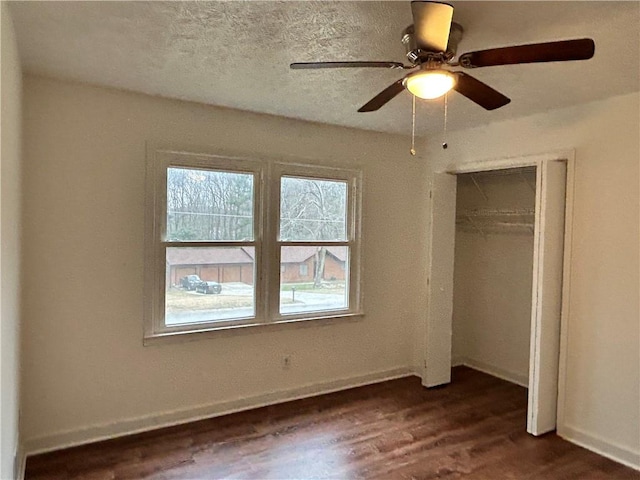 unfurnished bedroom featuring ceiling fan, a closet, dark hardwood / wood-style flooring, and a textured ceiling