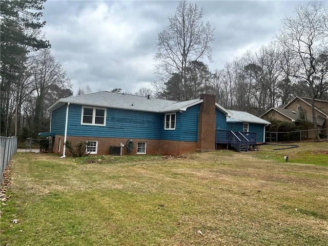 rear view of house featuring a wooden deck and a lawn