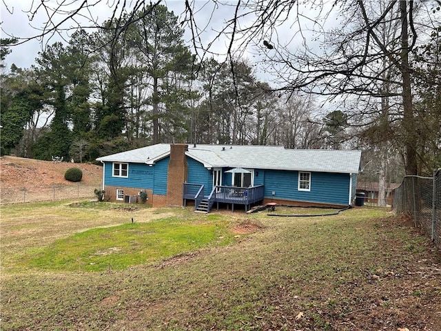 back of property featuring a deck and a lawn