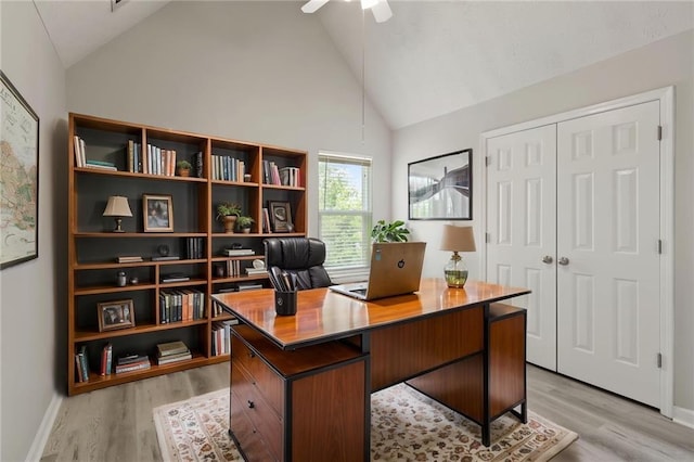 home office featuring light wood-style flooring, ceiling fan, baseboards, and high vaulted ceiling
