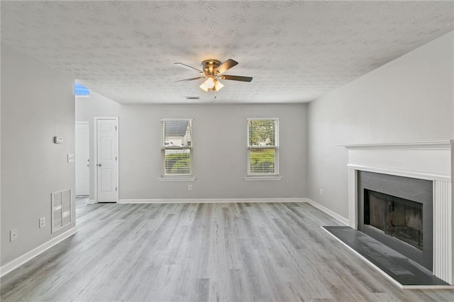unfurnished living room with a textured ceiling, a ceiling fan, wood finished floors, a fireplace, and baseboards