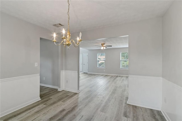 spare room with a chandelier, wood finished floors, a textured ceiling, ceiling fan, and baseboards