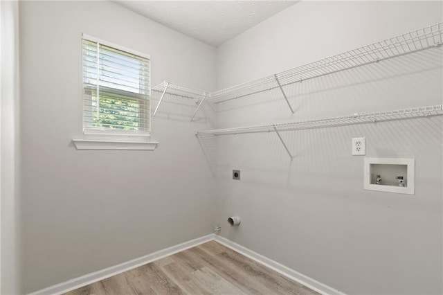 clothes washing area featuring electric dryer hookup, baseboards, wood finished floors, and washer hookup