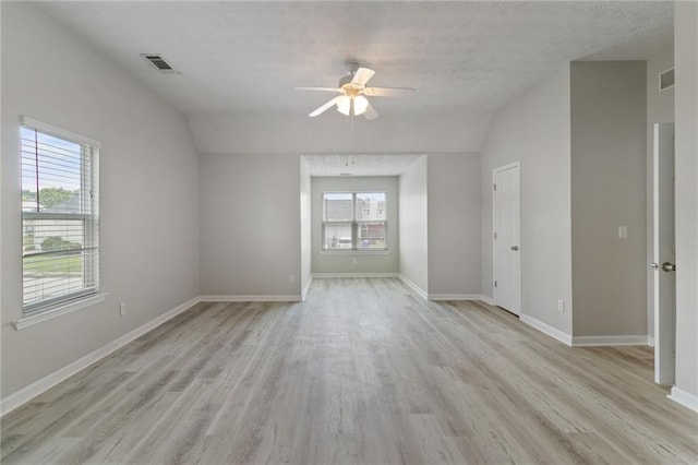 spare room featuring lofted ceiling, light wood finished floors, a ceiling fan, and baseboards