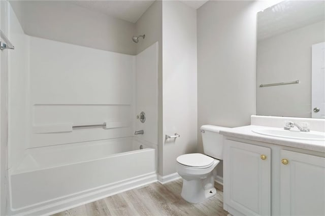 bathroom with shower / tub combination, toilet, wood finished floors, vanity, and baseboards