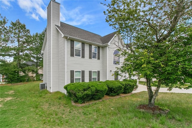 view of side of property featuring a chimney, central AC, and a lawn